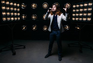 erkek şarkıcı parlak fenerler, çerçevede uzun saçlı sahne alanı üzerinde mikrofon ile sahne