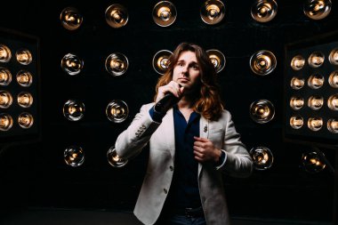 erkek şarkıcı parlak fenerler, çerçevede uzun saçlı sahne alanı üzerinde mikrofon ile sahne