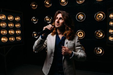 erkek şarkıcı parlak fenerler, çerçevede uzun saçlı sahne alanı üzerinde mikrofon ile sahne