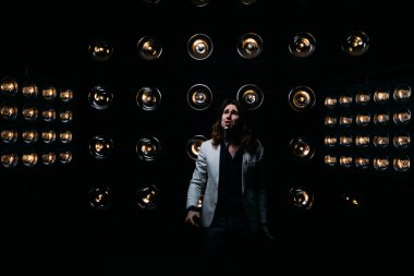 erkek şarkıcı parlak fenerler, çerçevede uzun saçlı sahne alanı üzerinde mikrofon ile sahne