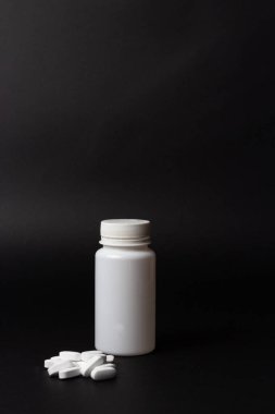 siyah arka plan üzerine bir beyaz hap şişe. depolama hapları. vitaminler. hapları bırakın. ve beyaz haplar, haplar yan yana yalan. Dikey görüntü
