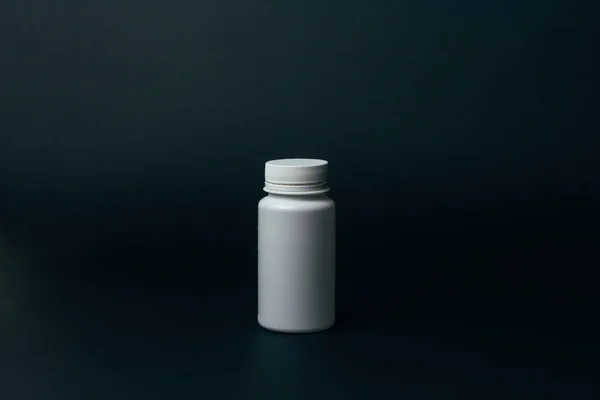one white pill bottle on black background. storage pills. vitamins. release pills.