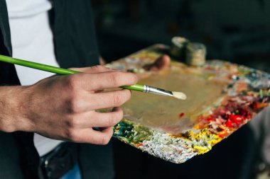 sanatçı bir palet boya ve bir fırça ile tutar ve canvas.to karışımı yağlı boya üzerinde boyayacağım