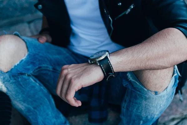 Hombre Mira Reloj Comprueba Hora Vaqueros Andrajosos Una Chaqueta Negra — Foto de Stock