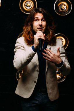 erkek şarkıcı parlak fenerler, çerçevede uzun saçlı sahne alanı üzerinde mikrofon ile sahne