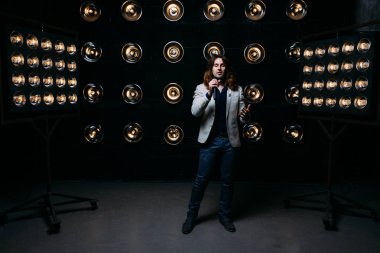 erkek şarkıcı parlak fenerler, çerçevede uzun saçlı sahne alanı üzerinde mikrofon ile sahne