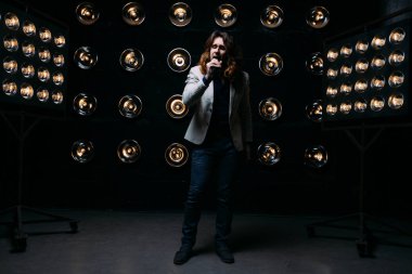 erkek şarkıcı parlak fenerler, çerçevede uzun saçlı sahne alanı üzerinde mikrofon ile sahne