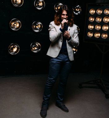 erkek şarkıcı parlak fenerler, çerçevede uzun saçlı sahne alanı üzerinde mikrofon ile sahne