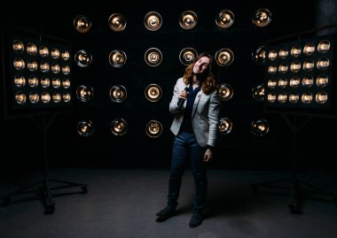 erkek şarkıcı parlak fenerler, çerçevede uzun saçlı sahne alanı üzerinde mikrofon ile sahne