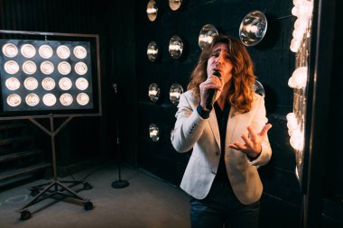 erkek şarkıcı parlak fenerler, çerçevede uzun saçlı sahne alanı üzerinde mikrofon ile sahne