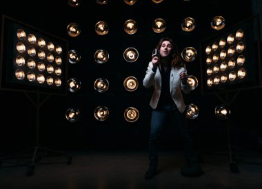 erkek şarkıcı parlak fenerler, çerçevede uzun saçlı sahne alanı üzerinde mikrofon ile sahne