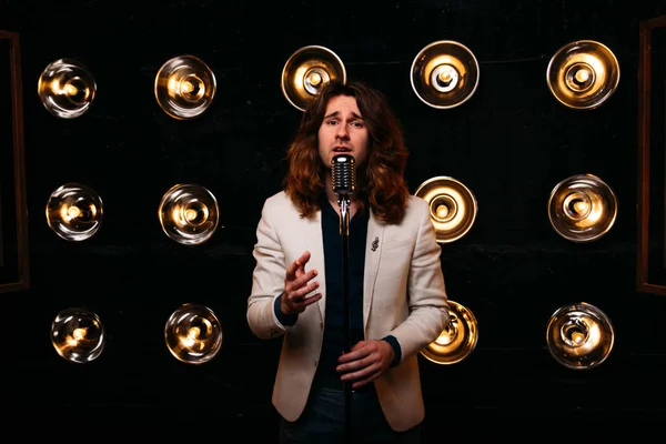 erkek şarkıcı parlak fenerler, çerçevede uzun saçlı sahne alanı üzerinde mikrofon ile sahne