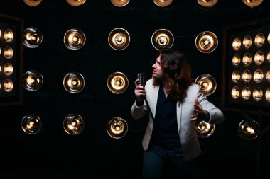 erkek şarkıcı parlak fenerler, çerçevede uzun saçlı sahne alanı üzerinde mikrofon ile sahne