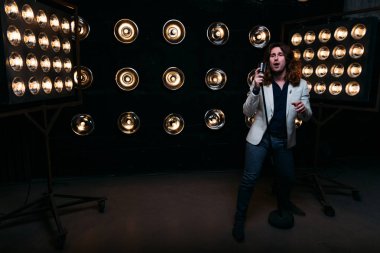 erkek şarkıcı parlak fenerler, çerçevede uzun saçlı sahne alanı üzerinde mikrofon ile sahne