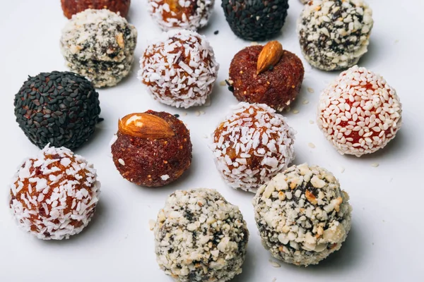 sweets from dried fruits with nuts and sesame seeds Tasty energy balls with dried fruits and nuts in coconut chips on a white plate