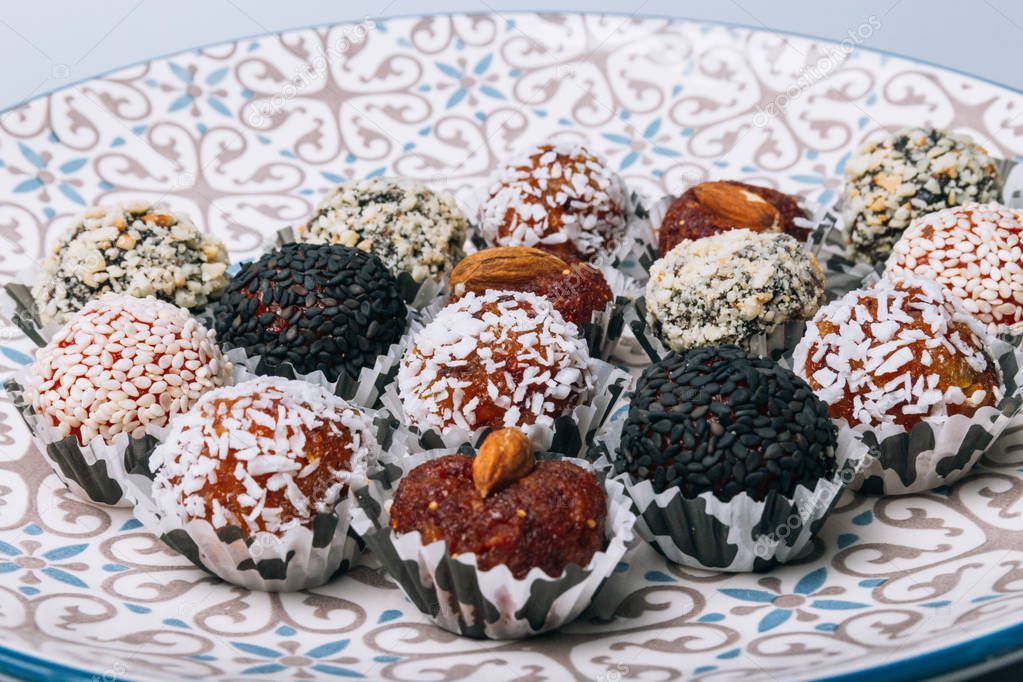 sweets from dried fruits with nuts and sesame seeds Tasty energy balls with dried fruits and nuts in coconut chips on a white plate