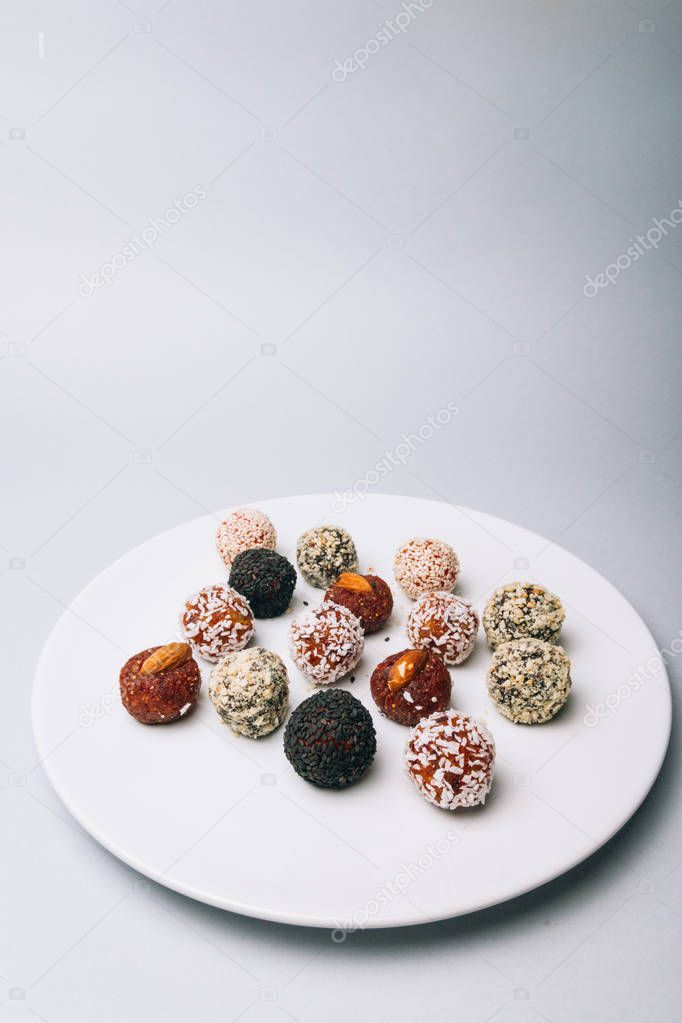sweets from dried fruits with nuts and sesame seeds Tasty energy balls with dried fruits and nuts in coconut chips on a white plate