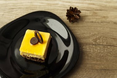 sarı buzlanma ve orada yanında siyah bir plaka üzerinde krem yalan ile çikolatalı kek vardır iki topaklar, dekorasyon, ahşap bir masa üzerinde