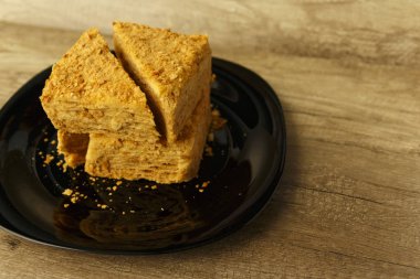 Ahşap masa, gıda arka plan üzerinde siyah plaka üzerinde turuncu pasta dilimi. Napolyon