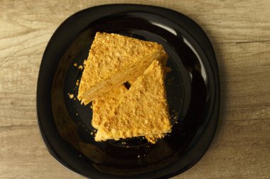 Ahşap masa, gıda arka plan üzerinde siyah plaka üzerinde turuncu pasta dilimi. Napolyon