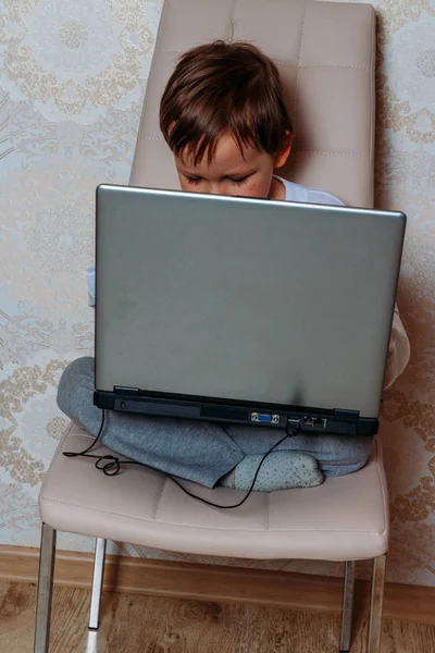 Menino Uma Camiseta Branca Senta Uma Cadeira Sofá Com Laptop — Fotografia de Stock