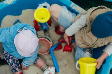 Çocuklar oyun alanında. kız ve erkek ise kum oyuncak topları, sovochkami, tırmıklar ve kovalar