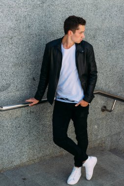 Korkuluk yakınındaki poz seksi adam. Yakışıklı delikanlı şık siyah elbise ve Beyaz Ayakkabı yakınındaki bir korkuluk poz