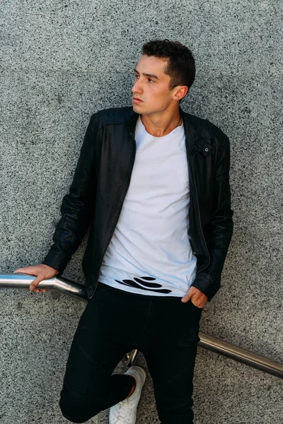 Korkuluk yakınındaki poz seksi adam. Yakışıklı delikanlı şık siyah elbise ve Beyaz Ayakkabı yakınındaki bir korkuluk poz