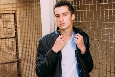 güzel ve çekici adam şehir kılavuzunda yakın duran, poz. siyah deri kurta, beyaz T-shirt, kot pantolon ve beyaz ayakkabı giymiş.