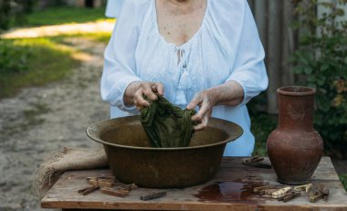Yaşlı bir kadın bahçede giysi yıkama. Beyaz vintage giyim. Taşra hayatı. elbise bir ip üzerinde kurur. Masanın yanındaki clothespins vardır. Stark'ın eski bir bakır lavabo ve kil sürahi.