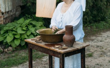 Yaşlı bir kadın bahçede giysi yıkama. Beyaz vintage giyim. Taşra hayatı. elbise bir ip üzerinde kurur. Masanın yanındaki clothespins vardır. Stark'ın eski bir bakır lavabo ve kil sürahi.
