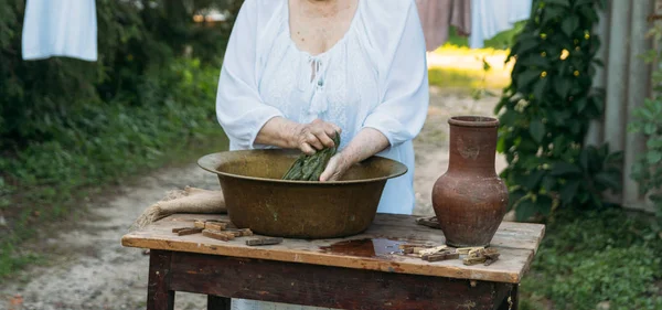 Yaşlı bir kadın bahçede giysi yıkama. Beyaz vintage giyim. Taşra hayatı. elbise bir ip üzerinde kurur. Masanın yanındaki clothespins vardır. Stark'ın eski bir bakır lavabo ve kil sürahi.