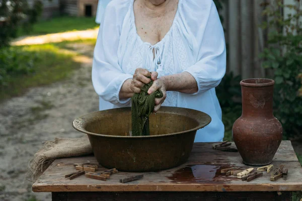 Yaşlı bir kadın bahçede giysi yıkama. Beyaz vintage giyim. Taşra hayatı. elbise bir ip üzerinde kurur. Masanın yanındaki clothespins vardır. Stark'ın eski bir bakır lavabo ve kil sürahi.