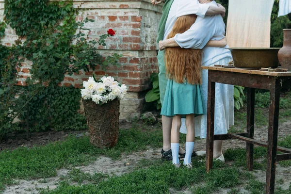 meeting grandmother and grandchildren. grandmother embraces grandchildren, brother and sister. grandson and granddaughter came to visit. give flowers. relatives meeting. Grandmother in white vintage clothing and grandchildren in green clothes. next t