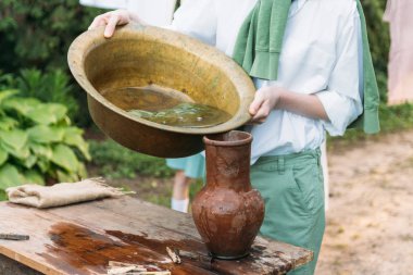 beyaz bir gömlek ve yeşil kazak, çocukta bir kil sürahi tutar, suyun dışında bakır lavabo içine dökülen. Yardım, kırsal. Köyü.