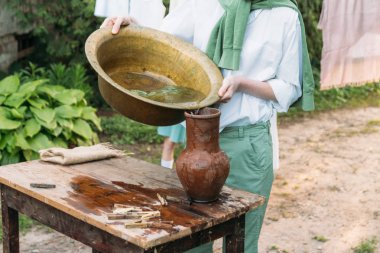 beyaz bir gömlek ve yeşil kazak, çocukta bir kil sürahi tutar, suyun dışında bakır lavabo içine dökülen. Yardım, kırsal. Köyü.