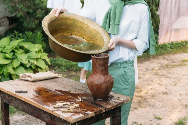 beyaz bir gömlek ve yeşil kazak, çocukta bir kil sürahi tutar, suyun dışında bakır lavabo içine dökülen. Yardım, kırsal. Köyü.