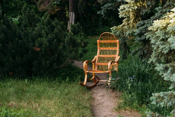 Hasır sallanan sandalye rattan yaptı. Eski sallanan sandalye ahşap. takas, orman yolu, yolun üzerinde ormanda yol üzerinde duruyor. Gizlilik ve rahatlama. El yapımı