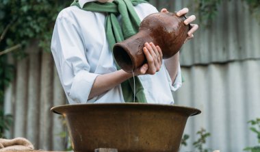 beyaz bir gömlek ve yeşil kazak, çocukta bir kil sürahi tutar, suyun dışında bakır lavabo içine dökülen. Yardım, kırsal. Köyü.
