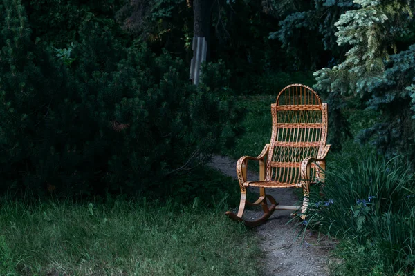 wicker rocking chair made of rattan. old rocking chair made of wood. stands on the road in the woods on the clearing, on the forest path, on the road. privacy and relaxation. handmade