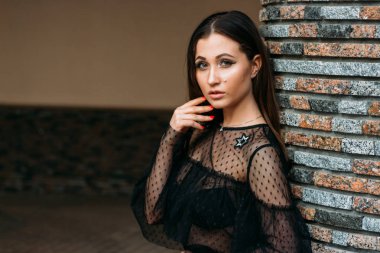 Genç ve güzel kadın moda şık portresi duygusal portresi. Şehir portre. üzgün kız. yıldızlar ve gezegenler bir elbise ile siyah bir elbise esmer. beklenti. rüyalar. Duvara yakın duruyor