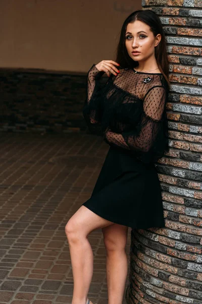 Genç ve güzel kadın moda şık portresi duygusal portresi. Şehir portre. üzgün kız. yıldızlar ve gezegenler bir elbise ile siyah bir elbise esmer. beklenti. rüyalar. Duvara yakın duruyor