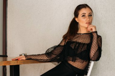 güzel esmer beyaz sandalye ahşap bir masada oturan. bir panel ve bir yıldız ile siyah bir elbise öyle. bir toplantı için bekliyor. Konumlandırma. Kadın portre. Cafe City