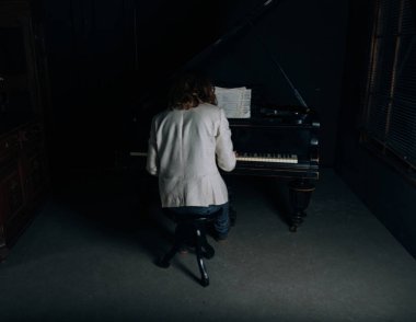 adamın yanında siyah bir piyano notlar görünüyor