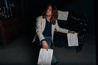 adamın yanında siyah bir piyano notlar görünüyor