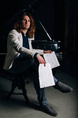adamın yanında siyah bir piyano notlar görünüyor