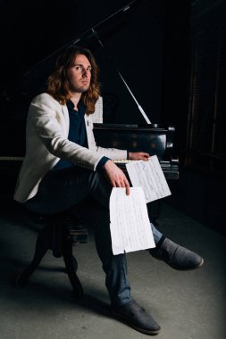 adamın yanında siyah bir piyano notlar görünüyor