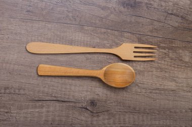 tahta kaşık ve çatal, çatal bıçak takımı ahşap bir masada vardır