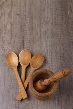 ahşap bir masa üzerinde bir ahşap stupa yanındaki üç tahta kaşıklar yalan. dikey atış. doğal malzeme, ekoloji. Menü, metin için yer