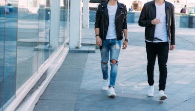 güzel ve çekici adam şehirde oluyor poz. siyah deri kurta, beyaz T-shirt, kot pantolon ve beyaz ayakkabı giymiş. ayna Binası yakınında. siyah gözlük şehirde dolaşmak. iletişim. Toplantı arkadaşlar.